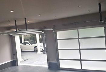 Interior view of a Mound garage with newly installed double electric glass garage doors, one partially open and a white sports car visible outside.
