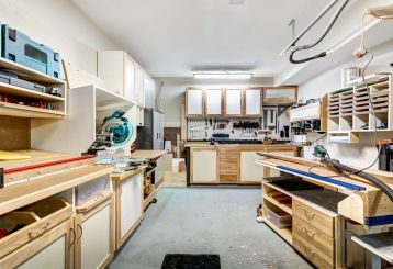 Spacious garage workshop in Mound, MN, featuring built-in cabinets, organized tool storage, wood workbenches, and overhead lighting for a clean, functional workspace.