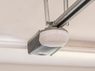 Ceiling-Mounted Automatic Garage Door Opener – Maintenance Tips Close-up of a modern automatic garage door opener mounted on the ceiling, showing the rail and motor system in a clean residential garage.